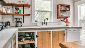A kitchen with a window, wooden shelves, a coffee maker, and a dish rack. - Nestled Victorian Historic Area (Guthrie)