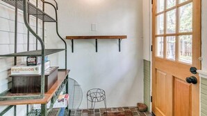A room with a wooden door, a window, a metal shelf, and a fan. - Nestled Victorian Historic Area (Guthrie)