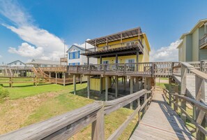 Eine Holzterrasse, die zwei Gebäude miteinander verbindet, mit blauem Himmel.