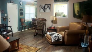A living room with a brown leather sofa, a wooden coffee table, and a dining area with wooden chairs and a table. - OLD DALLAS INN Charming 4-bedroom house, LARGE Dog friendly Backyard  (Elm Mott)