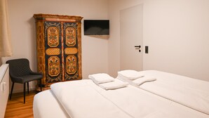 A hotel room with a bed, a TV mounted on the wall, a wardrobe, and a chair. - Domizil Deluxe Eleven (Kaprun)