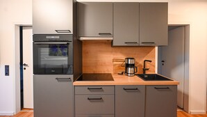 A compact kitchen with a built-in oven, a coffee maker, and a sink. - Domizil Deluxe Eleven (Kaprun)