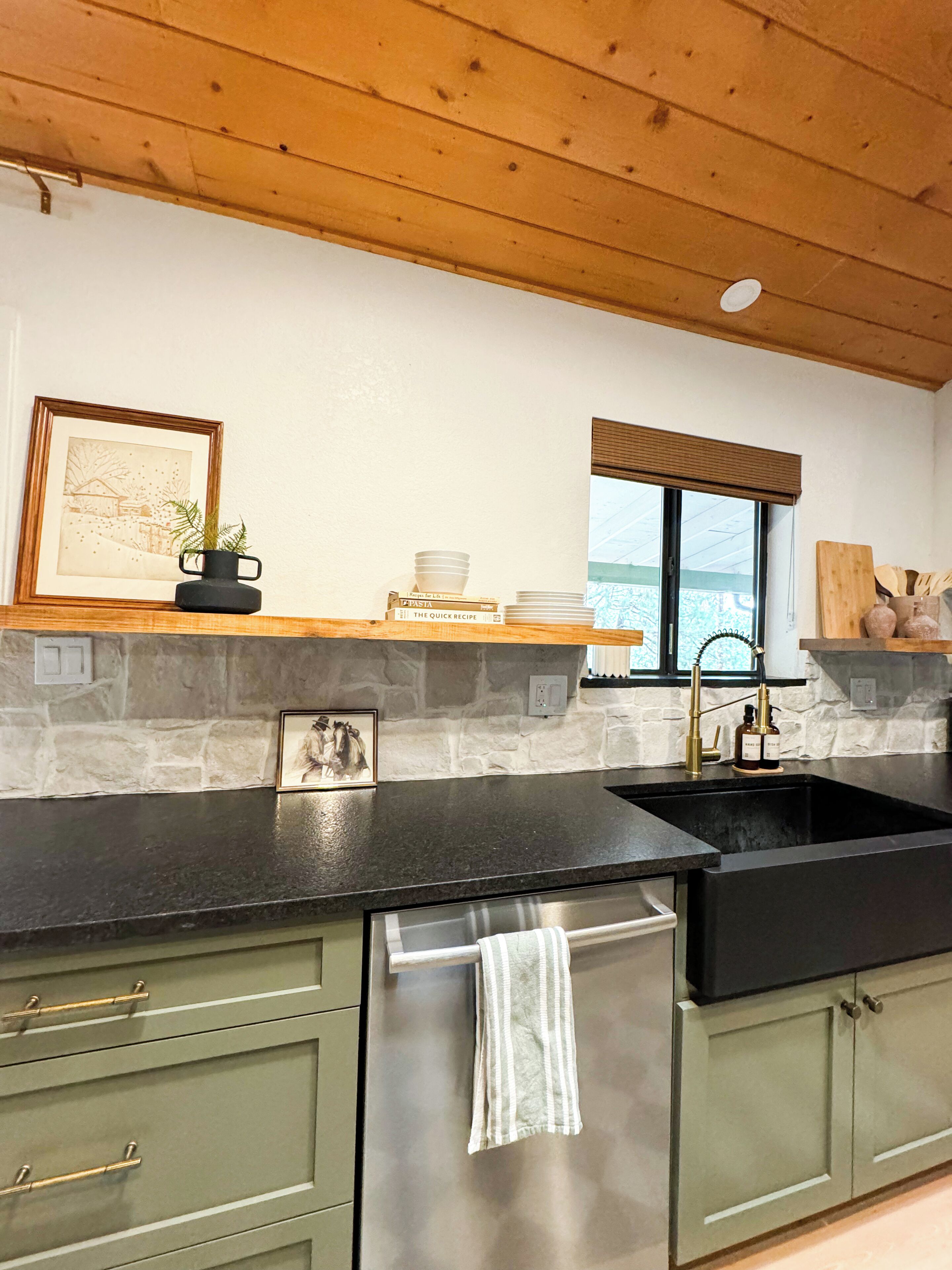 A kitchen with a stone backsplash, wooden ceiling, and a window with blinds.