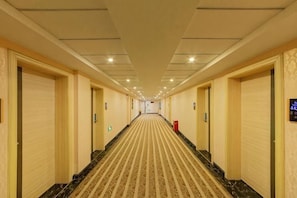 Un pasillo de hotel con pisos alfombrados, puertas a ambos lados y un techo de color claro.