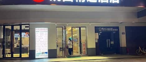 A hotel entrance with a signboard, glass doors, and a bicycle parked outside.