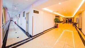 A hotel corridor with a marble floor, a reception desk, and a plant. - Changsha Xiaoyuan Selected Hotel (Changsha)