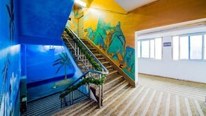 A staircase with a mural, a palm tree, and a patterned floor. - Changsha Xiaoyuan Selected Hotel (Changsha)