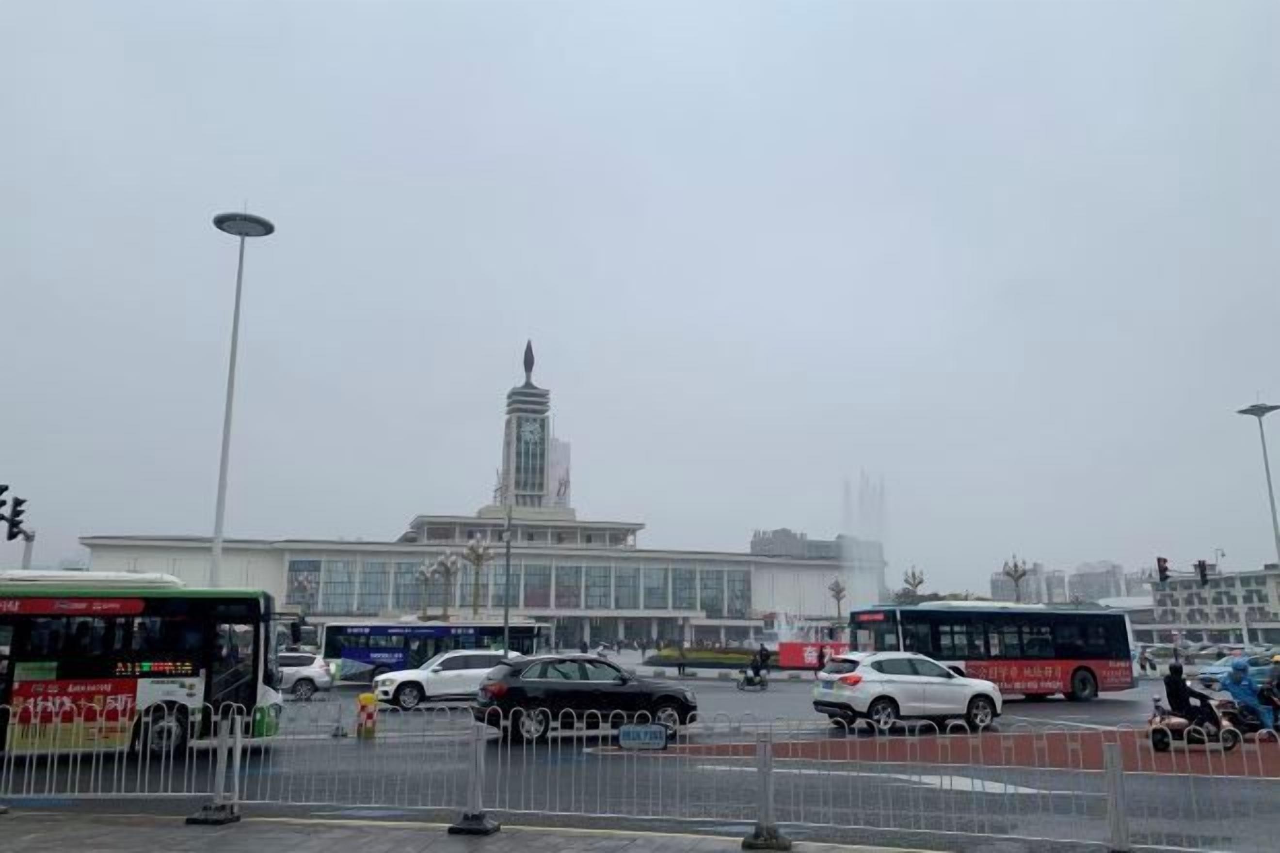 A busy urban street with a large building in the background, a bus, and several cars.