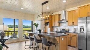 Una cocina moderna con armarios de madera, un refrigerador de acero inoxidable y una barra con taburetes.