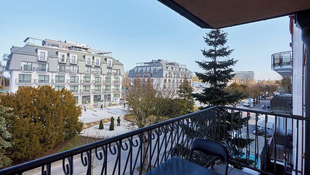 Un balcón con vista a edificios modernos y un árbol.