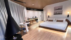 Een moderne slaapkamer met een bed, een bureau en een zwarte open haard.