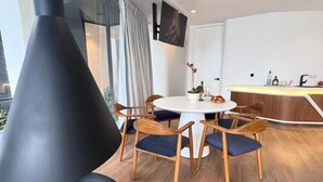 Een moderne eetruimte met een ronde tafel, zes houten stoelen met blauwe kussens, en een zwart, kegelvormig object op de vloer.