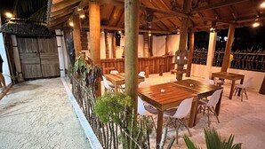 Ein Essbereich im Freien mit Holztischen und -stühlen, umgeben von einem Holzzaun und Pflanzen.