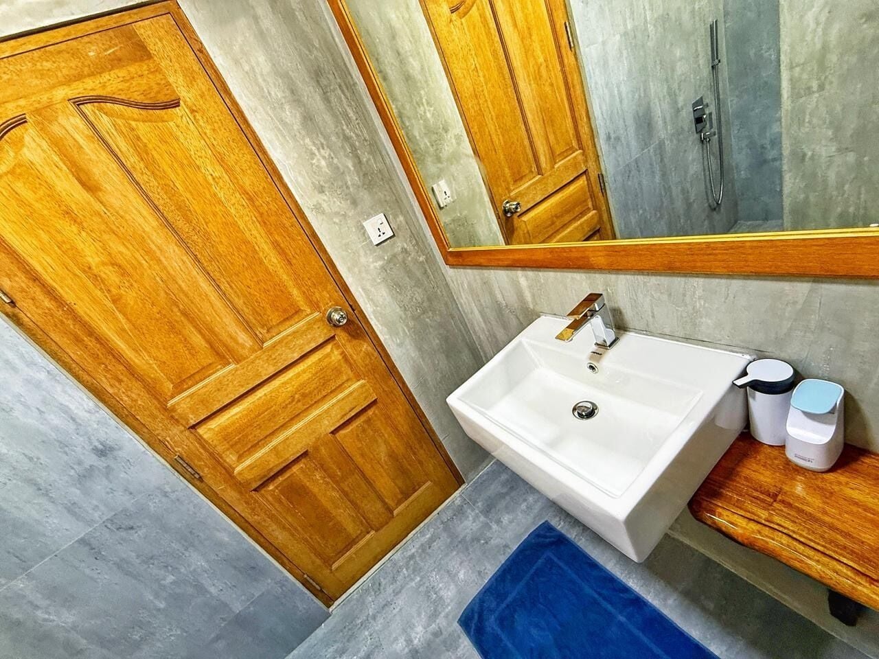 A bathroom with a wooden door, a white sink, a mirror, and a blue towel.