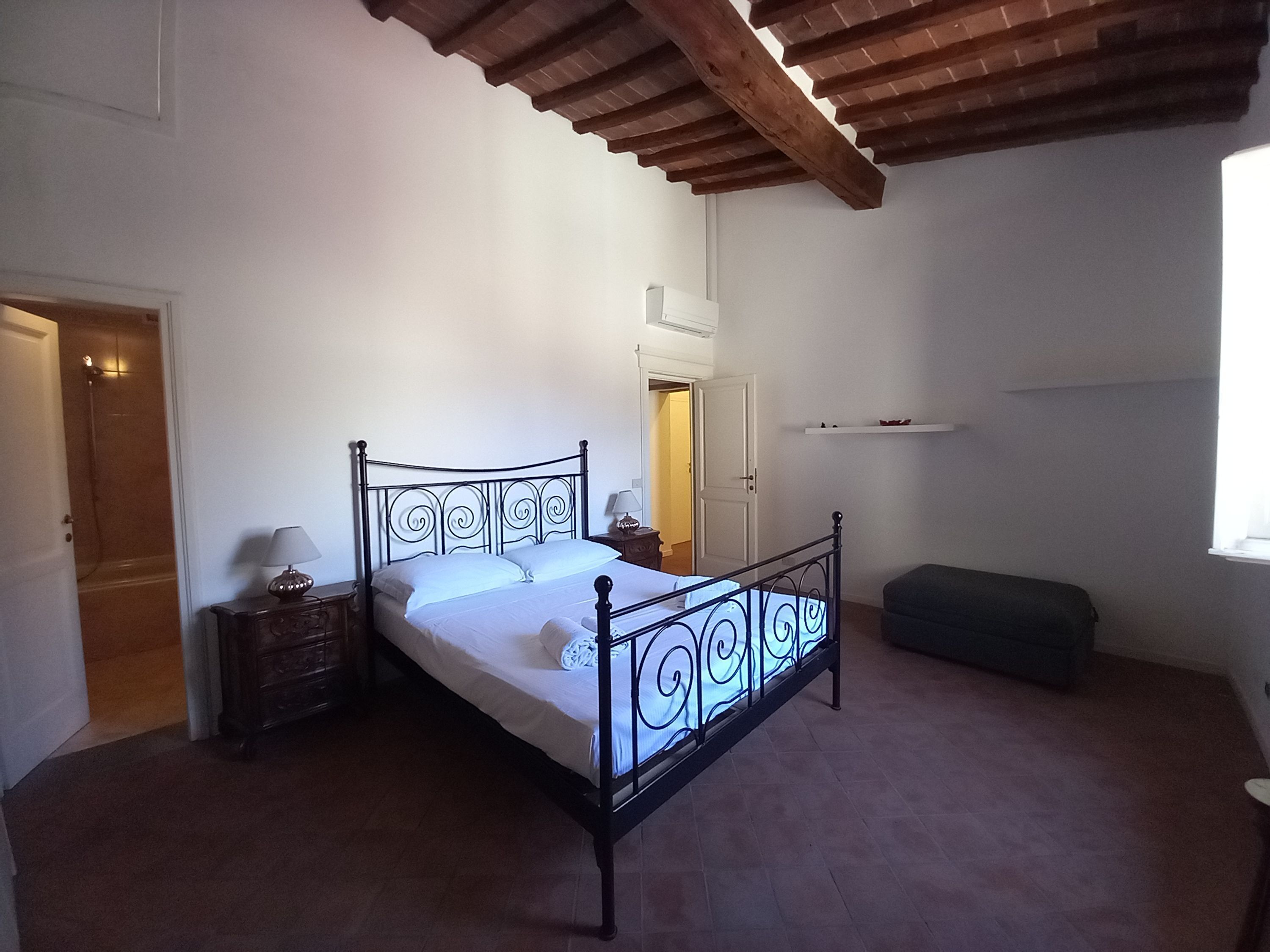 A bedroom with a bed, bedside tables, a bench, a door, and a window.