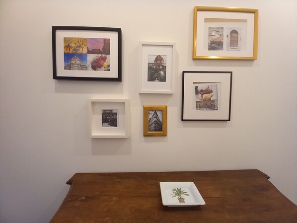A wall with six framed pictures of buildings and one framed picture of a building with a bicycle. - Porta Rossa in Firenze (Florence)