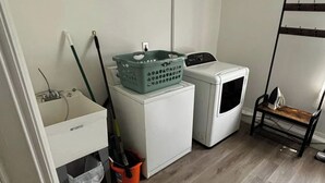 Et vaskerum med vaskemaskine, tørretumbler, vask og moppe.