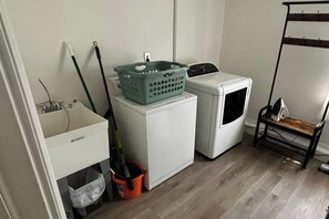 Un'area lavanderia con lavatrice, asciugatrice, lavandino e mocio.