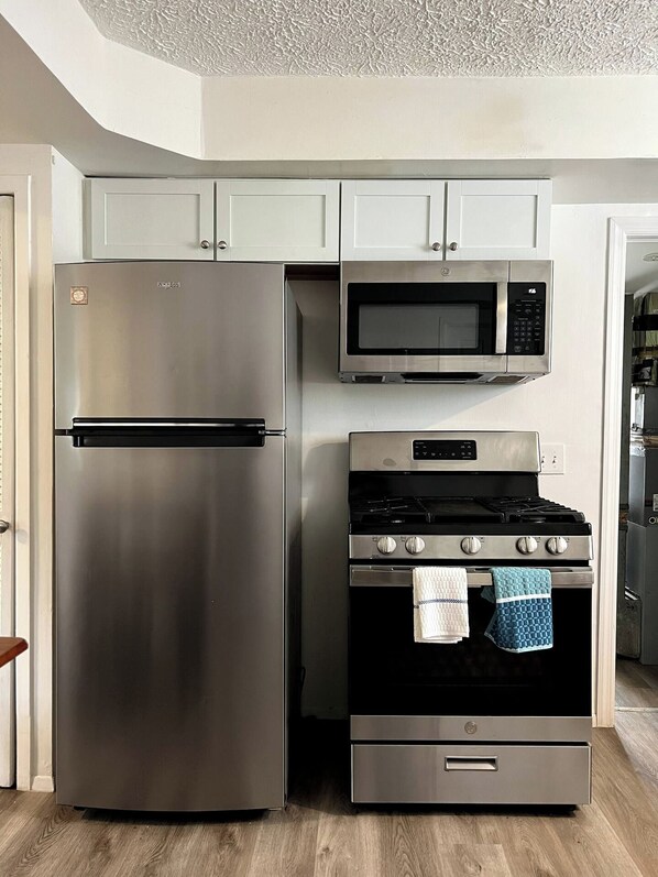 A kitchen with a stainless steel refrigerator, microwave, and stove.