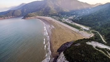 Een overzicht vanuit de lucht van een strand met een gebogen kustlijn, grenzend aan een bergketen.