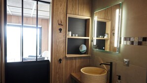 A bathroom with a wooden vanity, a round sink, a mirror, and shelves with toiletries. - Thoreau Suite - A Large Studio With Mountain Views (Aramits / Pyrénées Atlantiques)