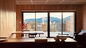 A wooden interior with a dining area, a view of mountains, and a large sliding door. - Thoreau Suite - A Large Studio With Mountain Views (Aramits / Pyrénées Atlantiques)