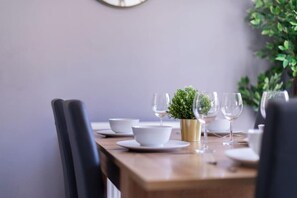 A dining table set with white bowls, wine glasses, and a small potted plant.