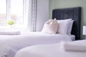 A hotel room with a large bed, a dark headboard, and a window with curtains.