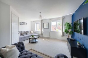 A living room with a grey sofa, a black coffee table, and a blue accent wall.