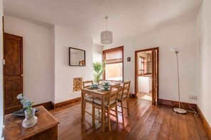 A dining area with a wooden table and chairs, a hanging light fixture, and a floor lamp. - Charming & Cosy Home | Free Wi-Fi & Great Location (Nottingham)