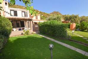 A two-story house with a tiled roof, a well-maintained lawn, and a garden area with a lamp post. - Villa Gioia in Costa Rei (Muravera)