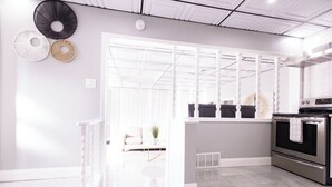A modern kitchen with a built-in oven, a white dining area with a sofa, and decorative wall art.