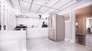 A modern kitchen with white cabinetry, stainless steel appliances, and a tiled floor.