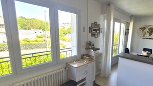 A room with large windows, a radiator, a small sink, and a shelf with items. - flat with two bedrooms, walking distance from the beach with parking and balcony (Perros-Guirec)