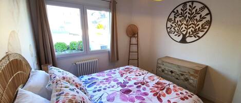 Ein Schlafzimmer mit Bett, Fenster, Heizkörper, einem Holzk dresser und einem Wandbild.