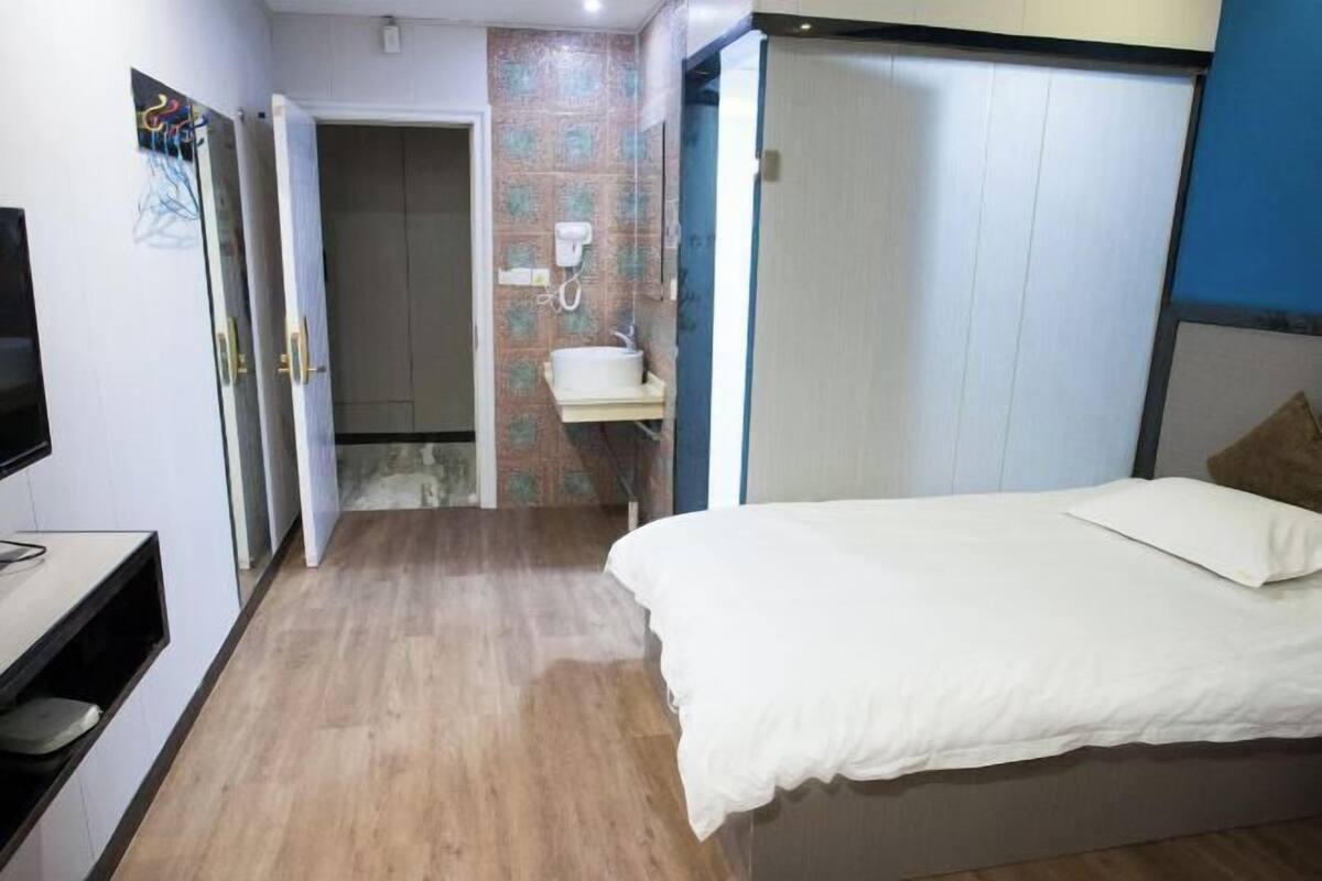 A bedroom with a bed, a bathroom with a sink, and a TV.