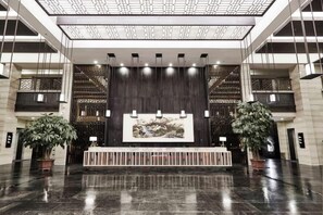 A spacious lobby with a reception desk, a large wall-mounted artwork, and potted plants. - Regao Hot Spring Hotel (Fushun)