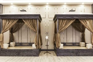 A room with two beds, each with a canopy, and a floor lamp between them.