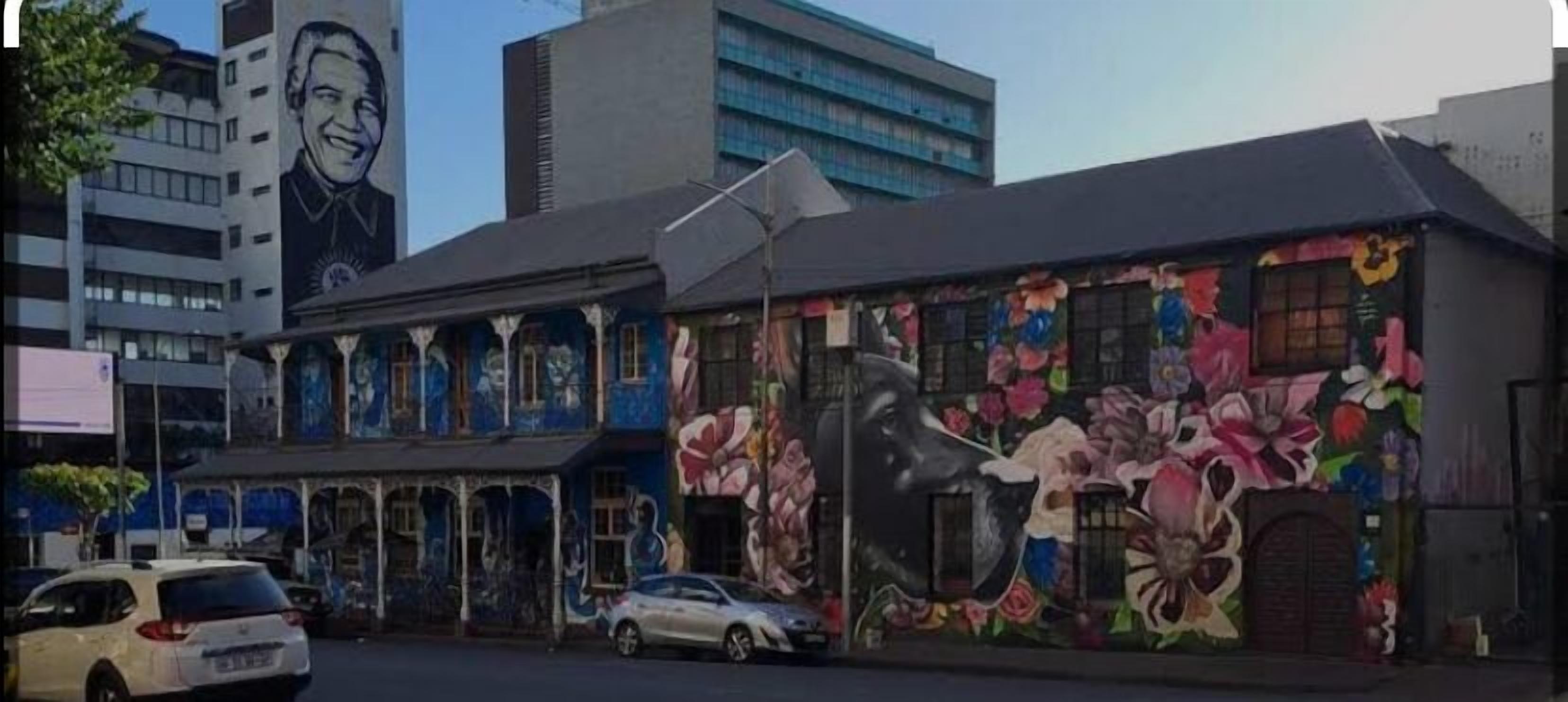 A building with a large mural of flowers and a portrait on the side.