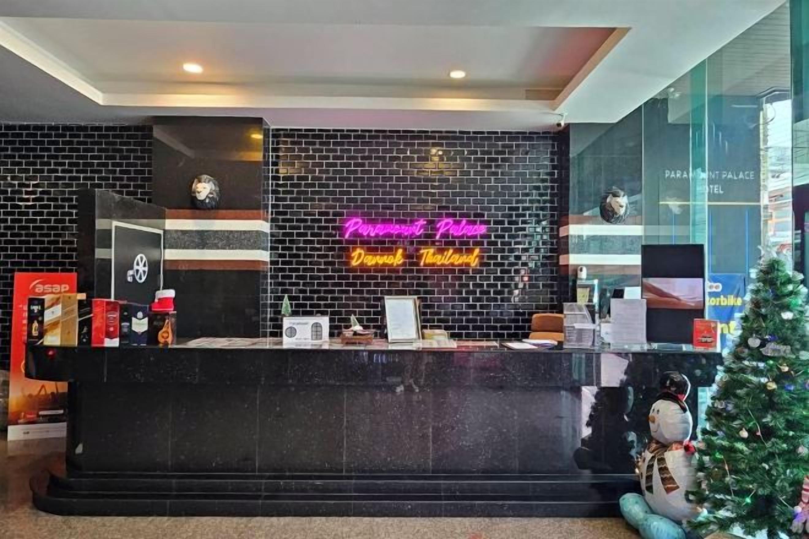 A hotel reception desk with a neon sign, a clock, and a Christmas tree.