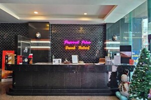 A hotel reception desk with a neon sign, a clock, and a Christmas tree.