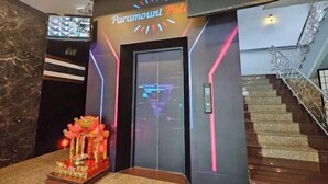 Ένας χώρος υποδοχής με την επιγραφή «Paramount Plaza», μια σκάλα και ένα διακοσμητικό βωμό με φώτα.