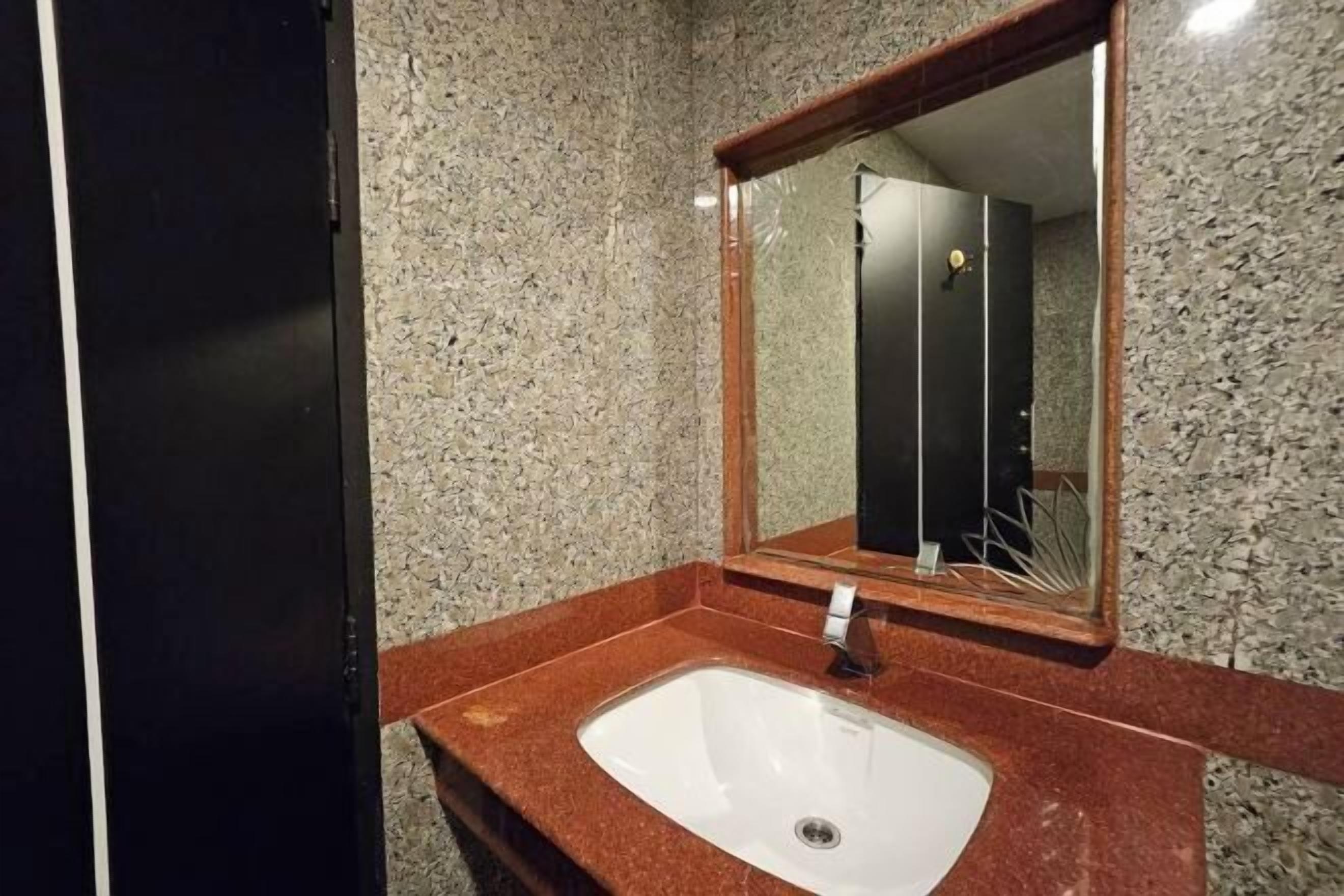 A bathroom with a granite countertop, a sink, and a mirror.