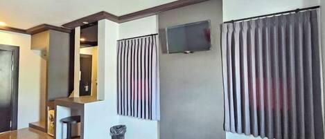 Un interior moderno con una zona de cocina, una barra y un televisor montado en la pared.