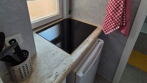 A compact kitchen with a black induction cooktop, a white dishwasher, and a window with frosted glass. - Appartamento al Centro di Roma Esquilino Colosseum Vicino Metro (Roma)