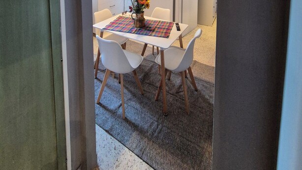 A dining area with a table set for two, a vase of flowers, and a hanging light fixture. - Appartamento al Centro di Roma Esquilino Colosseum Vicino Metro (Roma)