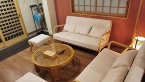 A room with a sofa, a round table, a small stool, and a chair. - Kokoro No Sato・Hitomi (Kyoto)