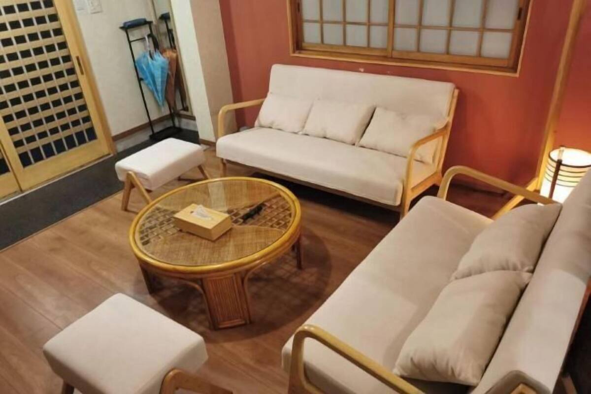 Una habitación con un sofá, una mesa redonda, un taburete pequeño y una silla.