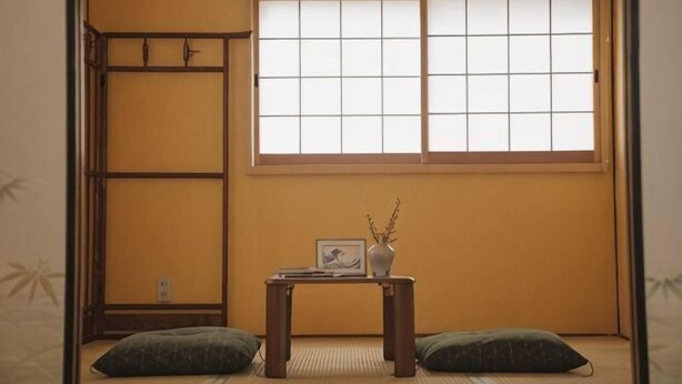 A traditional Japanese room with tatami flooring, a low table with a vase and picture frame, and a window with a grid pattern. - Kokoro No Sato・Hitomi (Kyoto)
