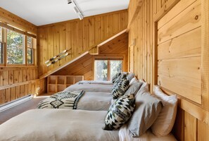 Een houten chalet met een slaapkamer op een entresol, een schuin dak en een ski-rek.